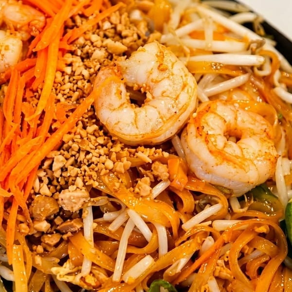 Shrimp Pad Thai with noodles, bean sprouts, carrots, crushed peanuts, and a lime wedge.